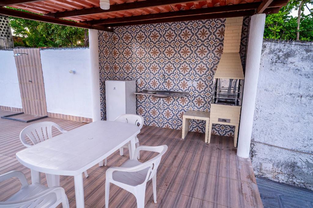 uma mesa branca e cadeiras em um deck de madeira em Casa a 950 m da Praia de Jauá - Espaçosa e Aconchegante! em Camaçari