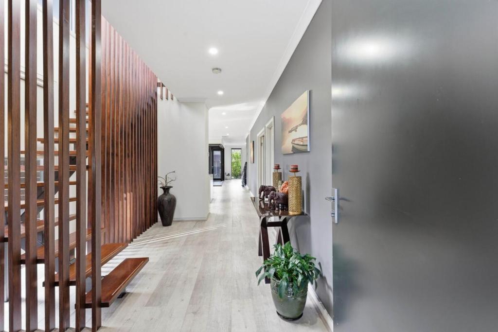 a hallway with white walls and wood floors and a staircase at Modern Family Retreat in Prime Williams Landing in Williams Landing