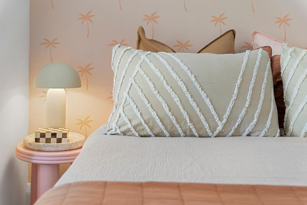a bed with a white pillow and a lamp on a table at Belles Bondi Beach Apartments - 1 and 2 Bedroom Stays - 500m to beach in Sydney