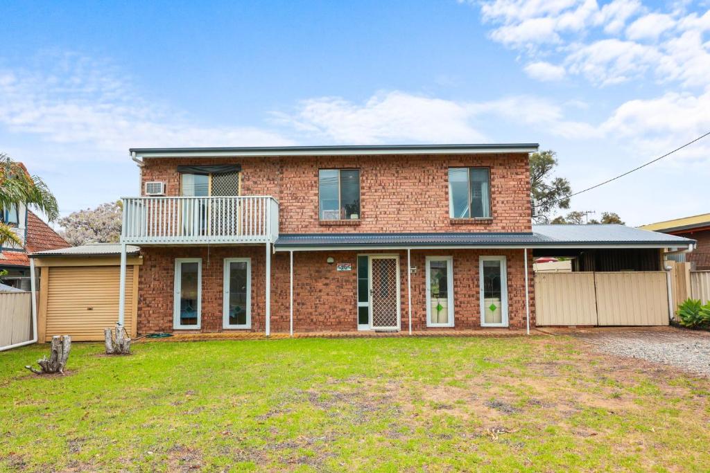 a brick house with a balcony and a yard at 36 Lacrington St, Goolwa Beach in Goolwa South
