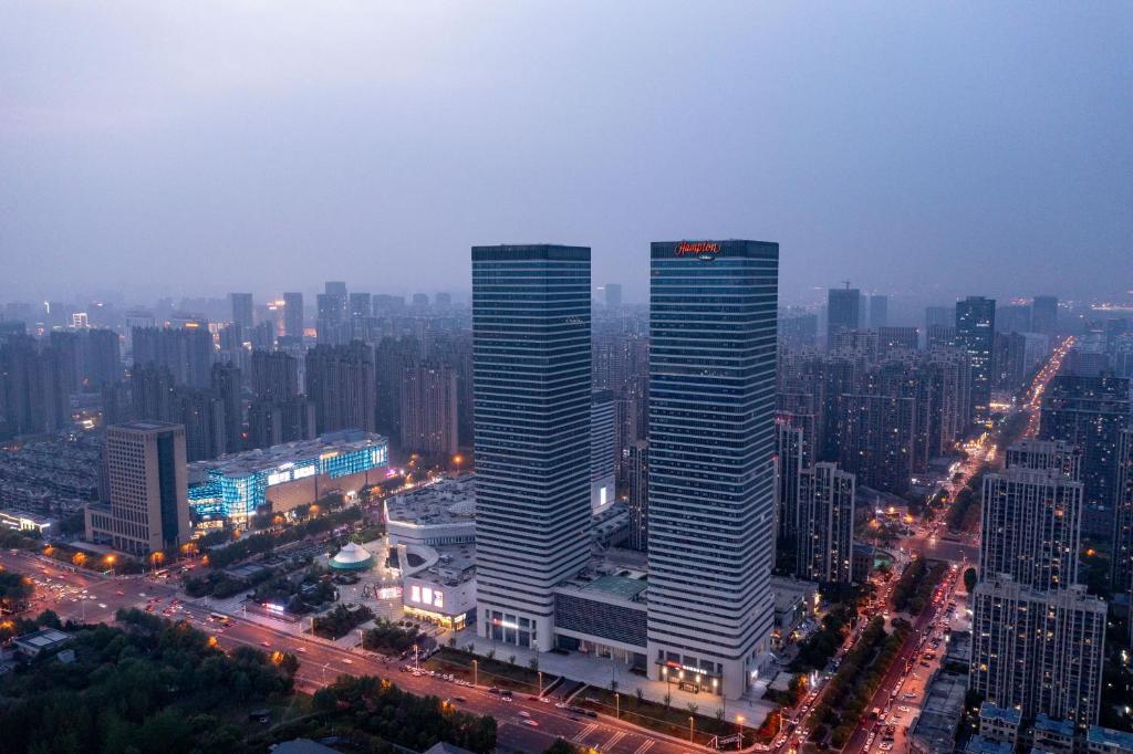 twee hoge wolkenkrabbers in een grote stad 's nachts bij Hampton by Hilton Hefei Binhu in Hefei