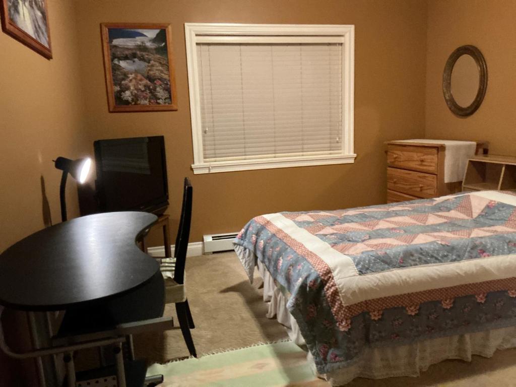a bedroom with a bed and a desk and a window at Barry and Elaine in Abbotsford