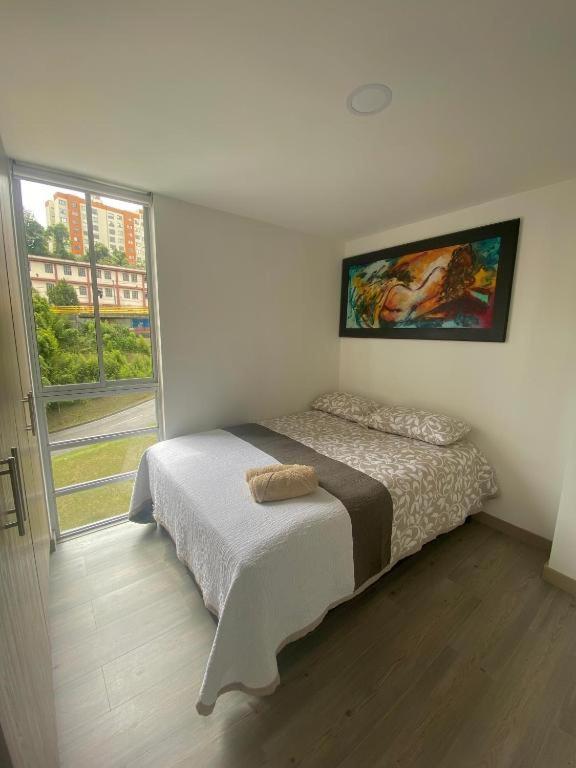a bedroom with a bed and a large window at Apartamento en Manizales in Manizales