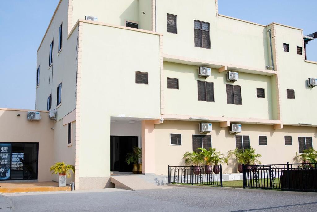 a white building with a black fence in front of it at Kwanskrom Villa Biggies Homes in Winneba