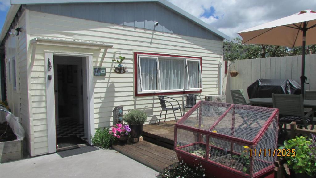 a small house with a wooden deck with an umbrella at Cozy Haven - Waihi in Waihi