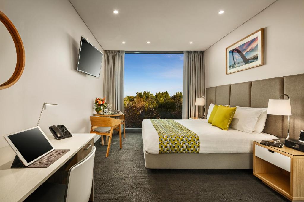 a hotel room with a bed and a desk with a laptop at Quest Mounts Bay Road in Perth