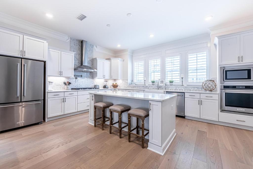 a kitchen with white cabinets and a large island with bar stools at Happily Eva After at Prominence 30A in Inlet Beach