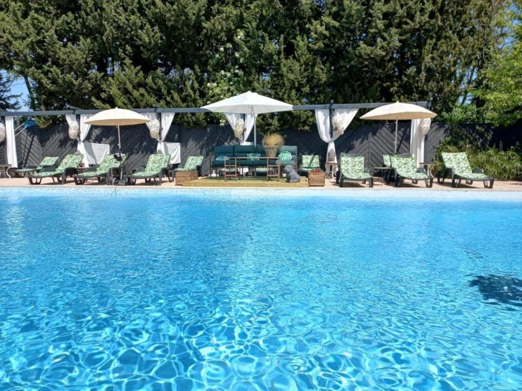 a pool of water with chairs and umbrellas at ZEcamping 4 étoiles pet friendly piscine et pétanque au cœur des Alpilles in Noves
