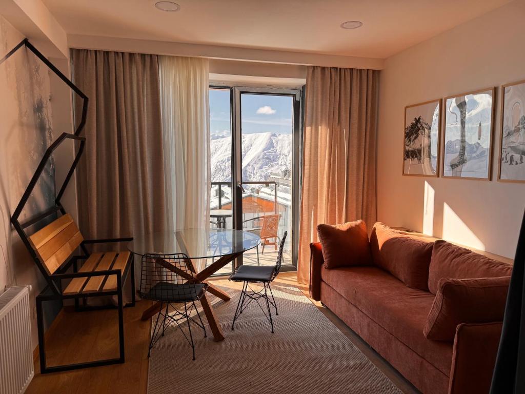 een woonkamer met een bank en een glazen tafel bij Ski Zoo Apartments, new gudauri in Kʼumlistsʼikhe