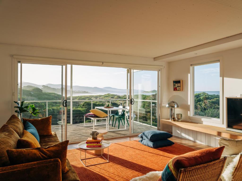 een woonkamer met een bank en een groot raam bij Frankie Beach House in Bicheno