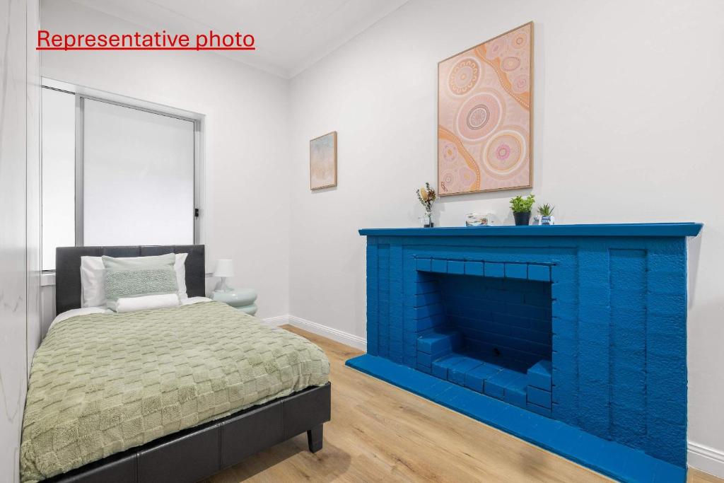 1 dormitorio con chimenea azul y 1 cama en Inviting Single Room with Sunlit Comfort - Matraville - Shared Bathroom and Kitchen, en Sídney