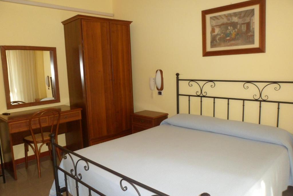 una camera con letto, scrivania e specchio di Albergo Miramonte a Vibo Valentia