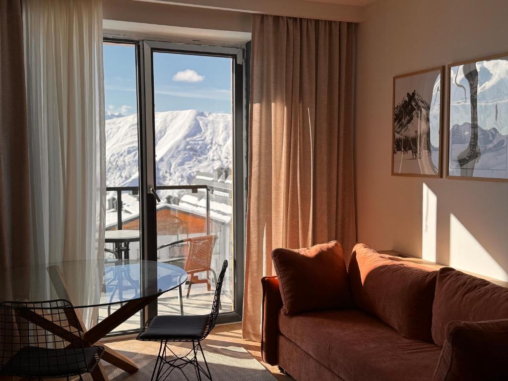 KʼumlistsʼikheにあるSki Zoo Apartments, new gudauriのソファとガラスのテーブルのあるリビングルーム
