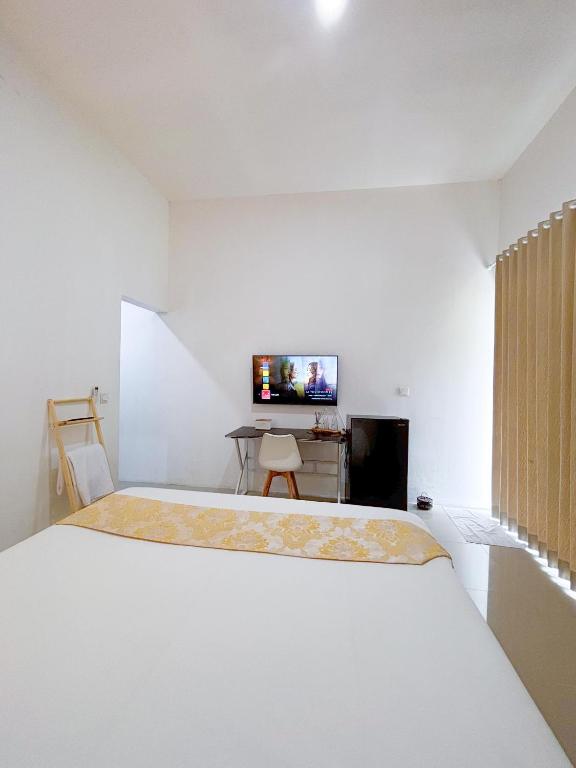 ein weißes Schlafzimmer mit einem Bett und einem Fernseher in der Unterkunft Yan Loft in Uluwatu