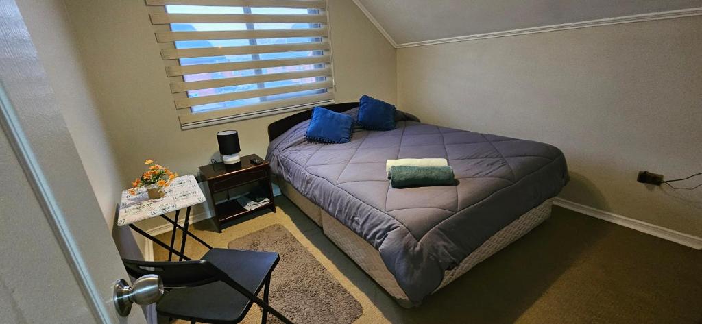 a bedroom with a bed with blue pillows and a window at Buen descanso cómodo y acogedor en Machali con Parcking y WIFI in Machalí