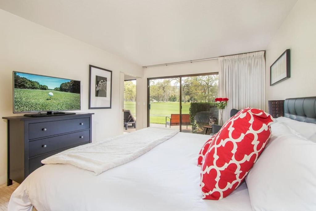 Un dormitorio con una gran cama blanca y un televisor. en Luxe Golf View Condo Prime Napa Location, en Vichy Springs