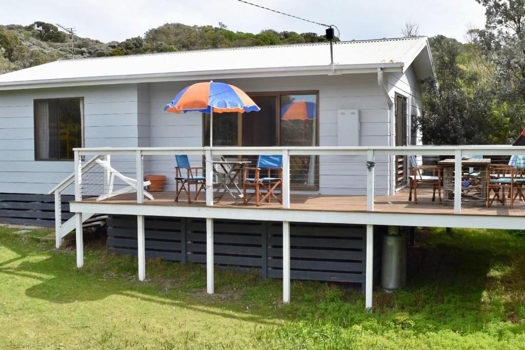 a house with a deck with a table and an umbrella at Manna Gum Beach House in Evergreen
