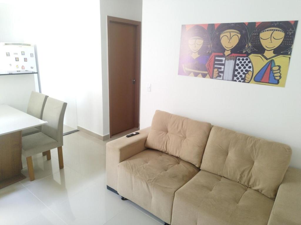 a living room with a couch and a painting on the wall at FLAT ACONCHEGANTE poucos min da praia in Maceió