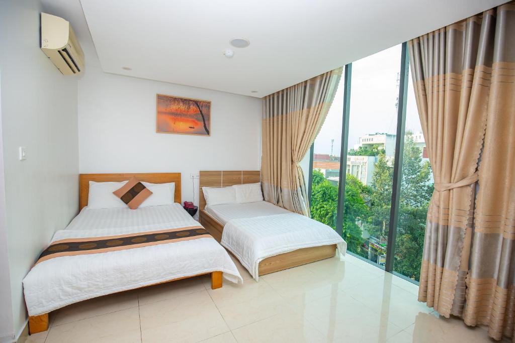 two beds in a room with a large window at Ruby Star Hotel Apartment in Vung Tau