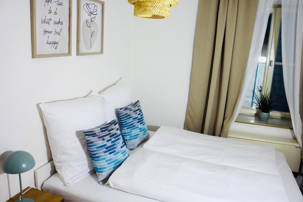 a white bed with two pillows sitting next to a window at Central Apartment Nördlingen in Nördlingen