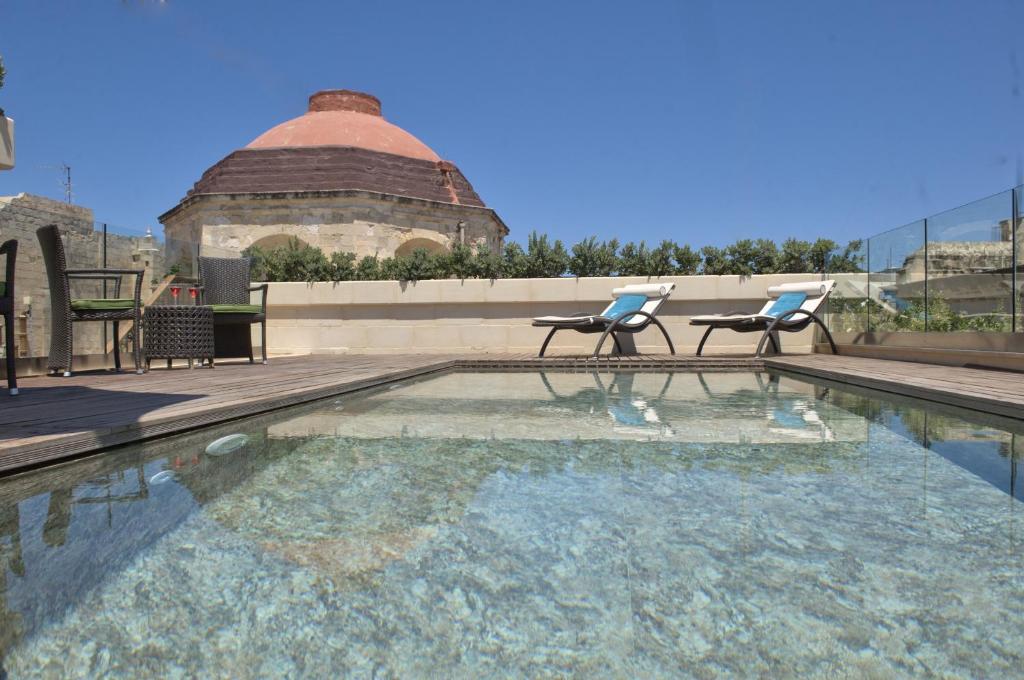 una piscina con 2 sillas y un edificio en Palazzo Consiglia - IK Collection, en La Valeta