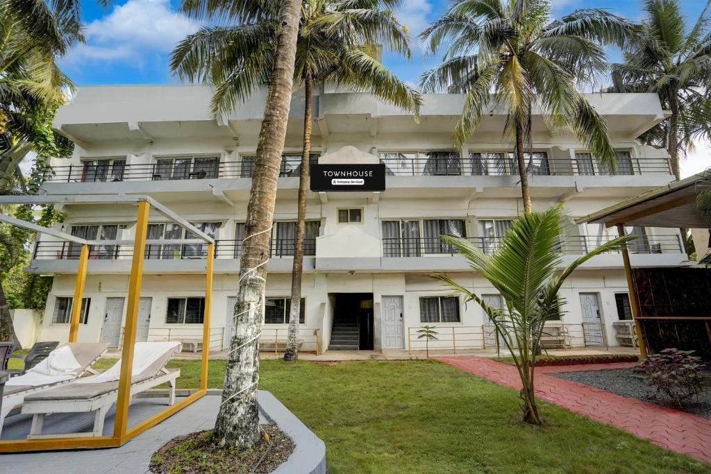 ein Gebäude mit Palmen davor in der Unterkunft Townhouse Morjim Beach North Goa Formerly Bay Breeze Hotels & Resorts in Chopdem