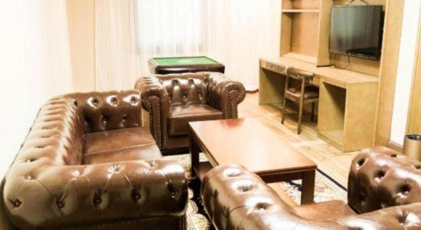 a living room with leather furniture and a flat screen tv at James Joyce Coffetel Baoding Railway Station in Baoding