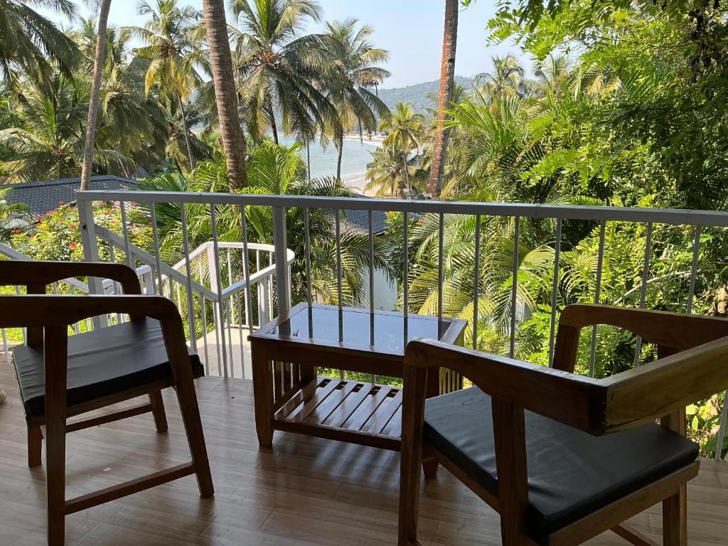 a balcony with two chairs and a table and a view of the ocean at Ourem Palace in Palolem