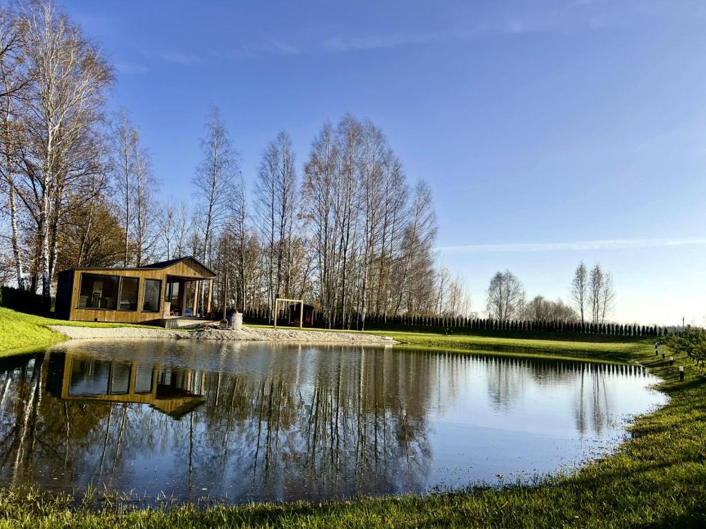 een kleine vijver met een gebouw ernaast bij Pas Milėją 