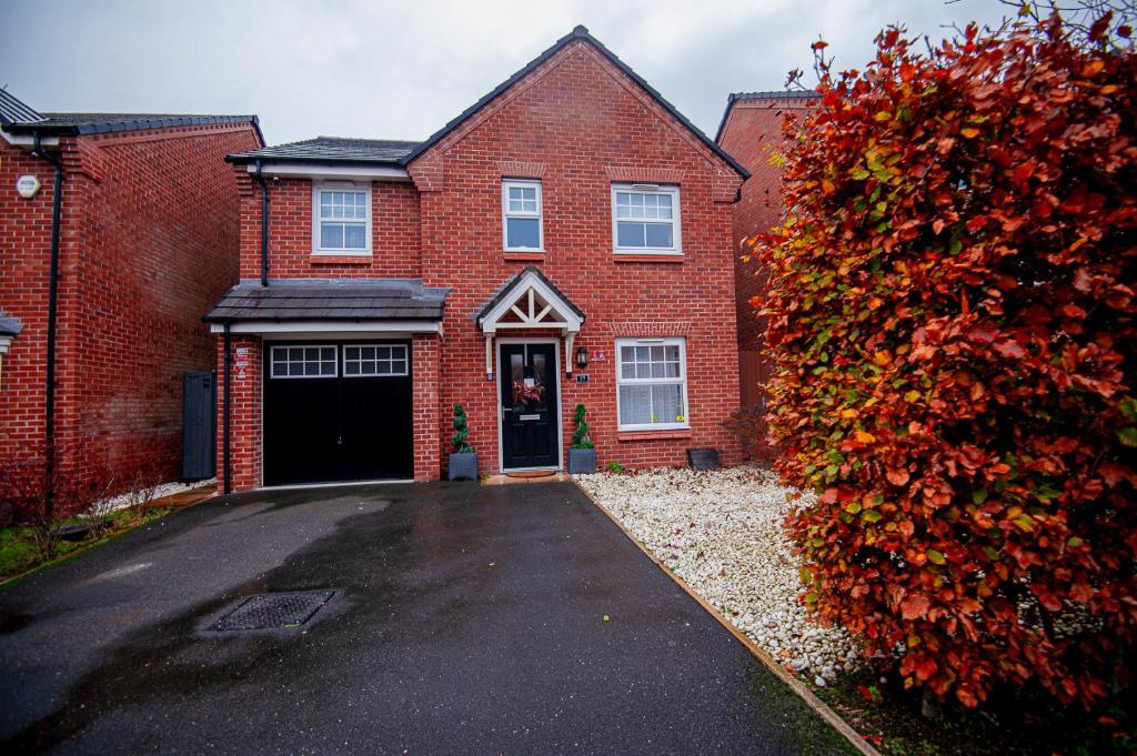 une maison en briques rouges avec un garage noir dans l'établissement PG Stays - Spacious Rooms with Shared Facilities, à Wigan