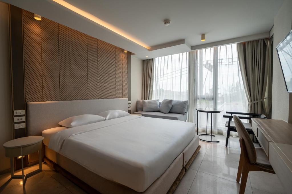ein Schlafzimmer mit einem großen weißen Bett und einer Couch in der Unterkunft Bluphere Residence by Prop Hopper in Na Jomtien
