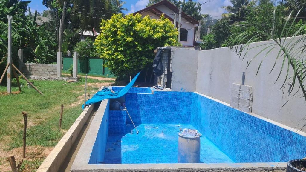 a blue pool with a water slide in a yard at Indunil Family Residence With Pool Hiriketiya in Dickwella