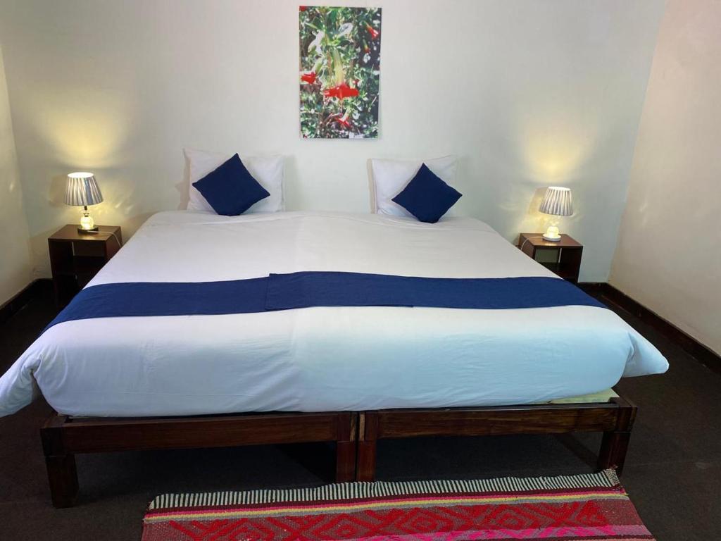 a bedroom with a large white bed with blue pillows at Runa House in Cusco