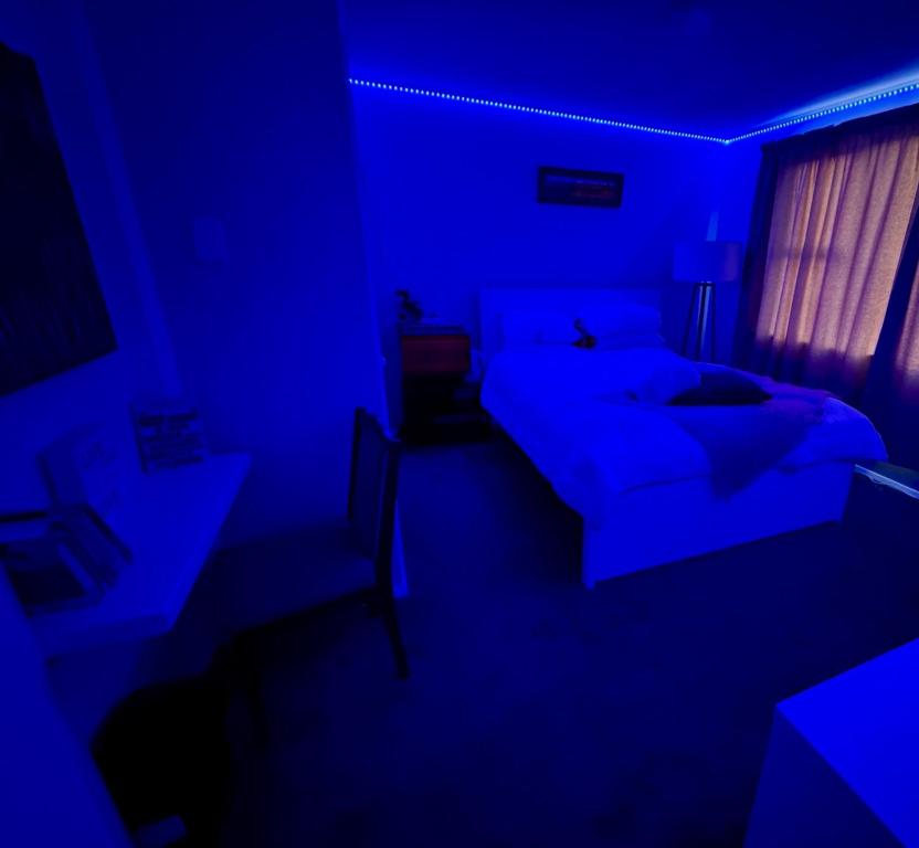 a blue room with two beds and a chair at Casa Carterton in Carterton
