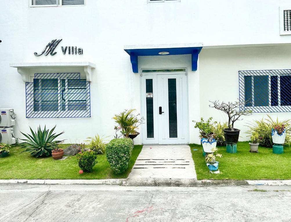 ein weißes Haus mit einer Eingangstür mit Pflanzen in der Unterkunft KGH Villa Rental in Cuayan