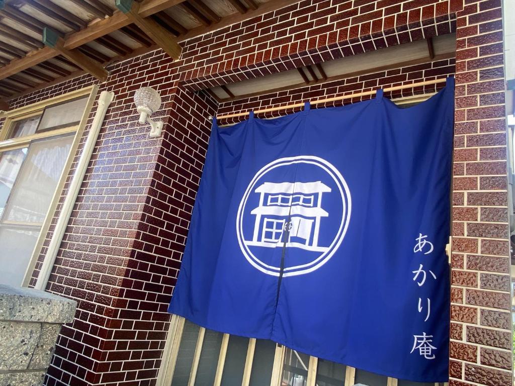 ein blaues Banner an der Seite eines Backsteingebäudes in der Unterkunft あかり庵 in Iki
