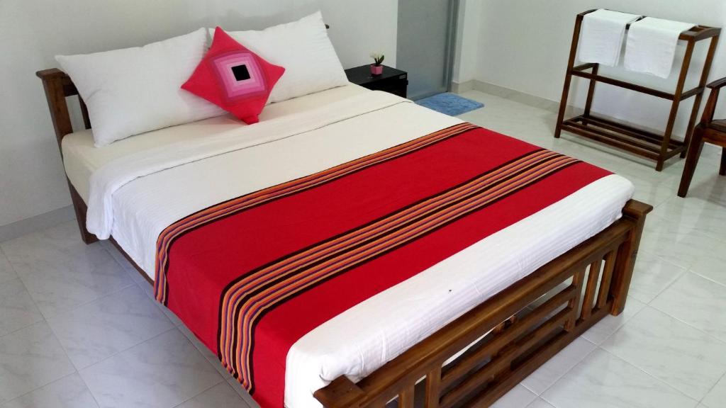 Radha Tourist Home في بولوناروا: سرير في غرفة عليها مخدة حمراء