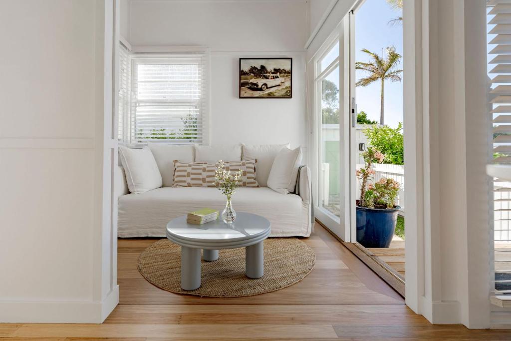 a living room with a white couch and a table at The Bunkie @ Ethel & Odes in Bundeena