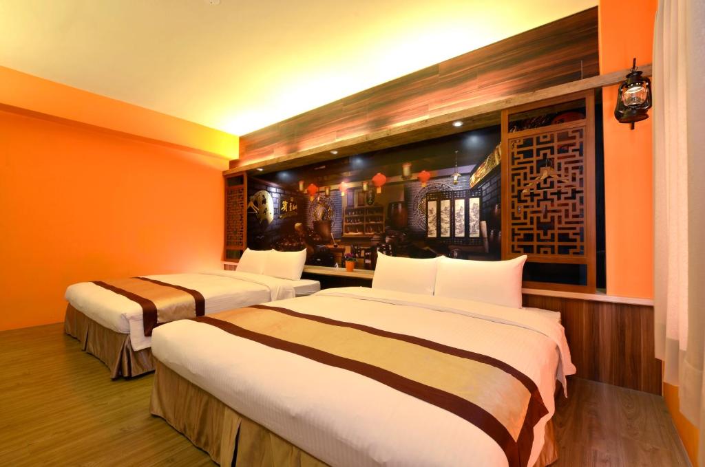 台中的住宿－西悠飯店台中店，橙色墙壁客房的两张床