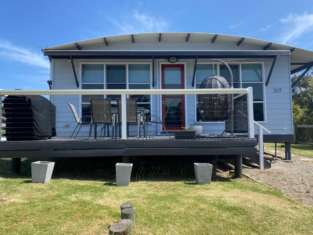 une petite maison avec une véranda, une table et des chaises dans l'établissement The Songbird, à Evergreen