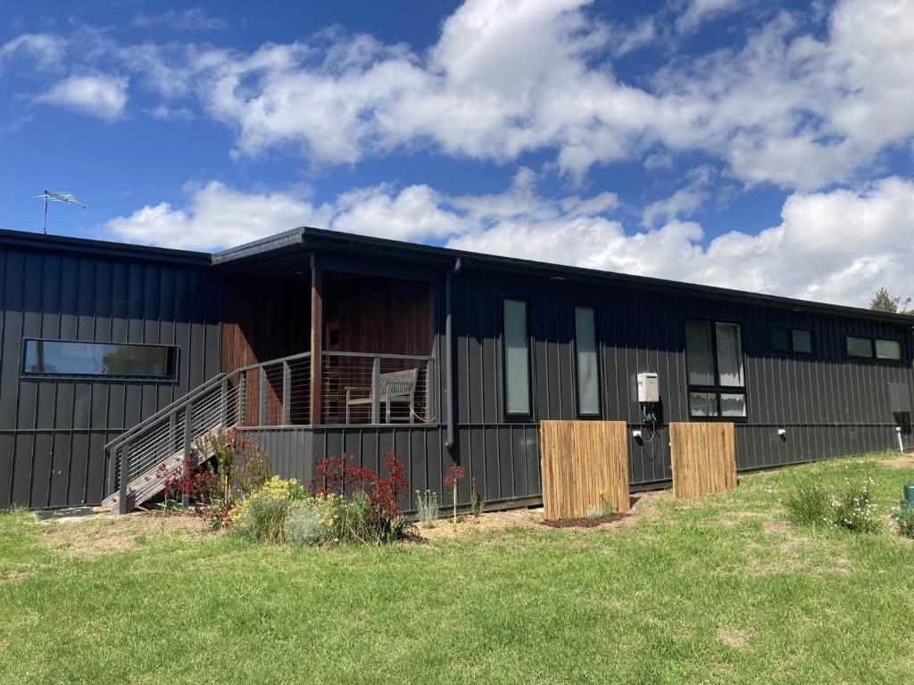 a black building with a porch and a yard at Ngurra in Evergreen