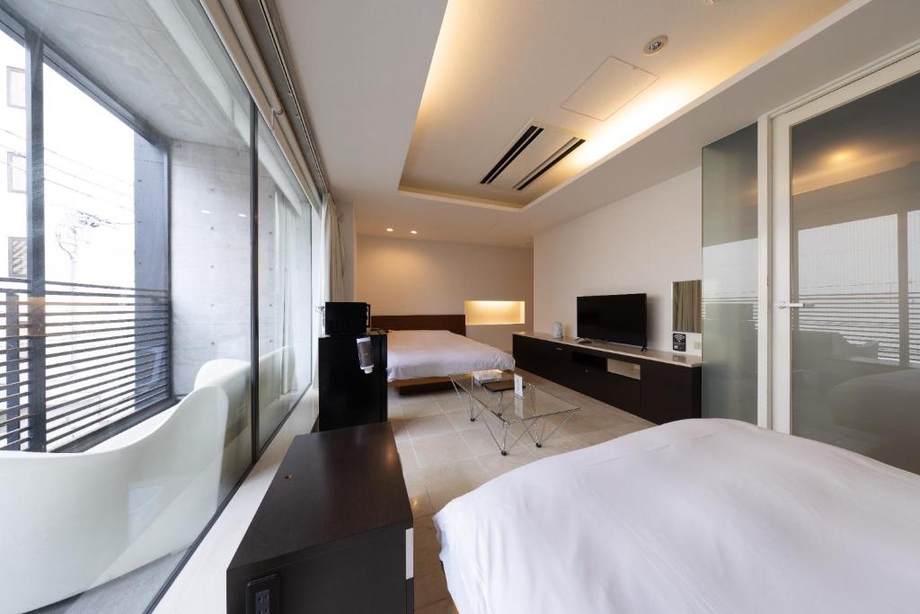 een hotelkamer met twee bedden en een televisie bij Huntelia Matsuyama in Matsuyama