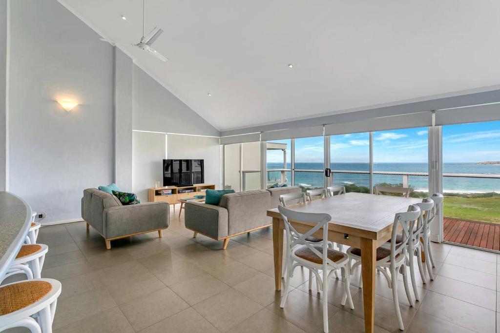 a dining room with a table and chairs and the ocean at 115 Seagull - Beachfront - Wi-Fi - No Linen Included in Hayborough