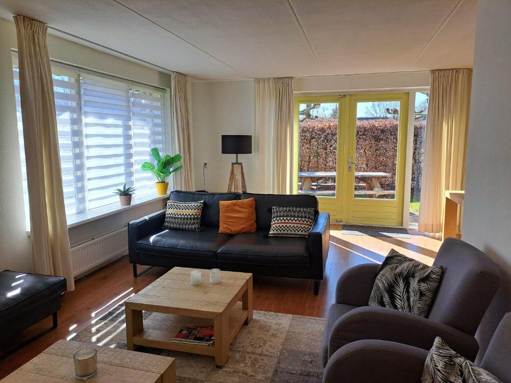 ein Wohnzimmer mit Sofa und Tisch in der Unterkunft Comfortabel landhuis voor rust en ontspanning in Schoonloo