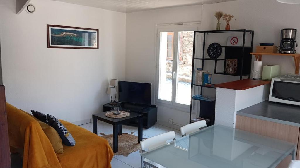 een woonkamer met een bank en een glazen tafel bij Petite maison Quartier Ste Croix in Josselin