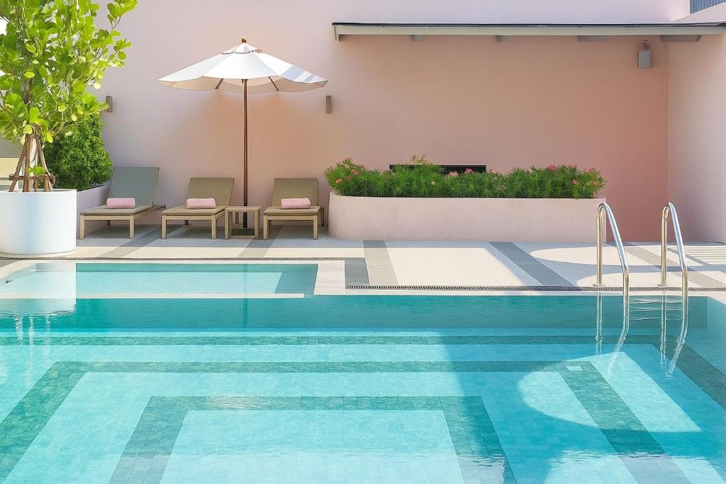 A rooftop-looking outdoor pool with loungers, an umbrella and planted borders.