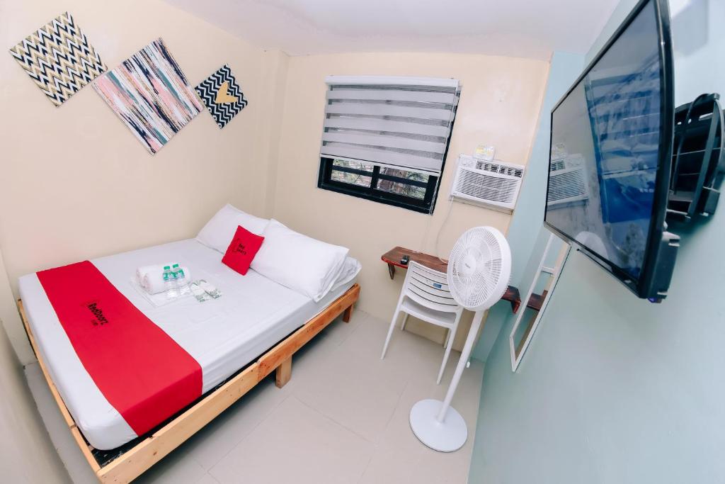 a small bedroom with a bed and a television at RedDoorz near Mariners Legazpi in Legazpi