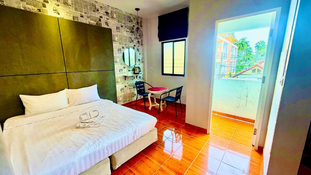 a bedroom with a bed and a table and a room at Cozy Bay Rawai in Phuket Town