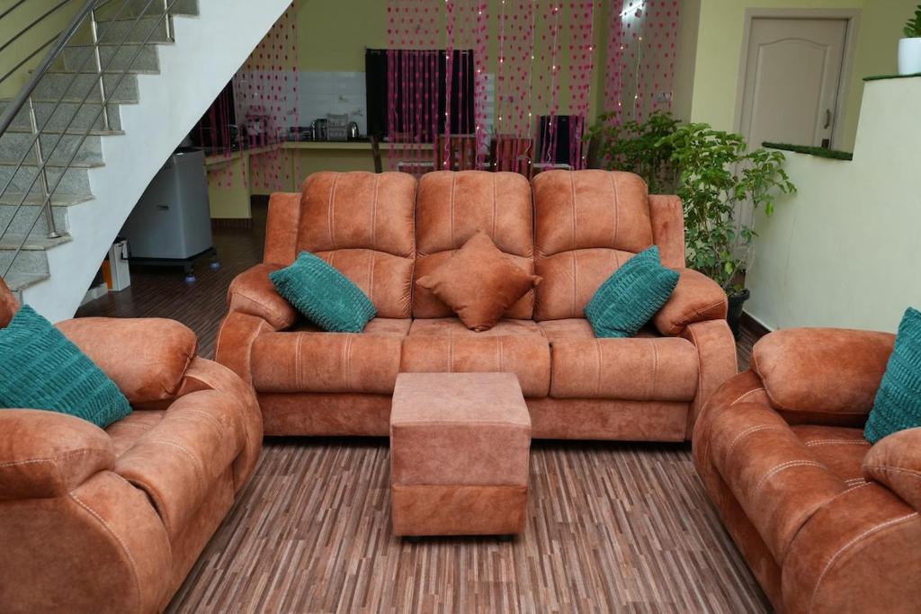 Una sala de estar con un sofá marrón y una mesa. en Deepam Haven Inn, en Gūduvāncheri
