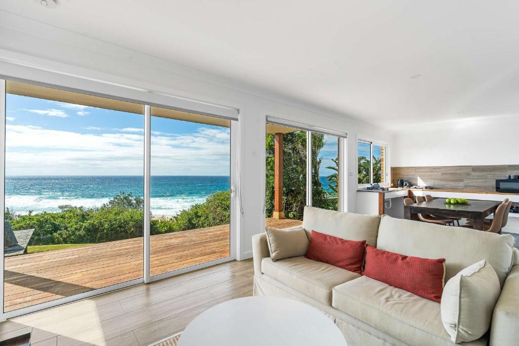 a living room with a couch and a view of the ocean at Waters Edge - beachside home near Rennies Beach in Ulladulla